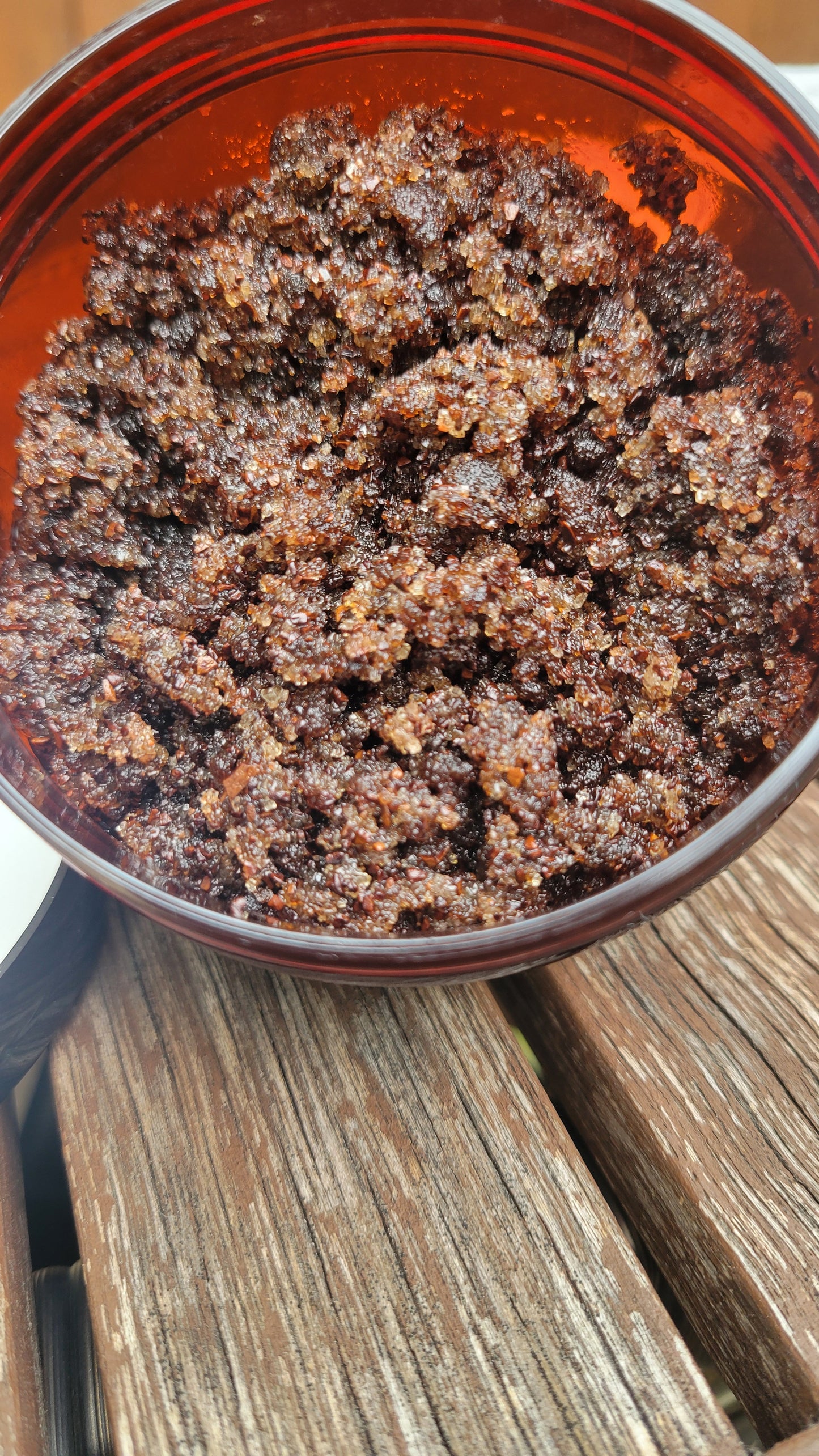 Jar of brown sugar vanilla coffee body scrub with visible texture, surrounded by natural ingredients like coffee beans and vanilla pods.